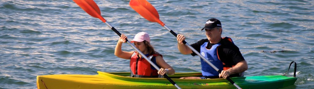 Padre e hija realizando piragüismo en el lago